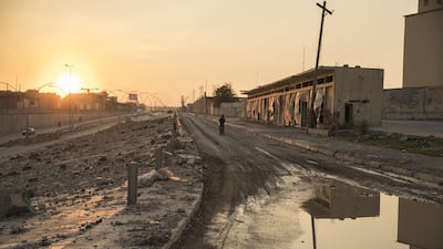 A person stands in a street next to damaged buildings in West Mosul, Iraq. Bloomberg
