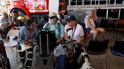 Lisa, Ray and Lucia West and their dog wait to be taken off the island. Getty / AFP