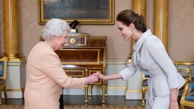 Actress Angelina Jolie is presented with the Insignia of an Honorary Dame Grand Cross of the Most Distinguished Order of St Michael and St George by Queen Elizabeth. Getty