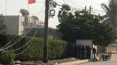 Pakistani paramilitary forces and police take cover behind a wall during an attack on the Chinese consulate in Karachi on November 23, 2018. Reuters