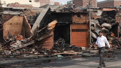A man walks among debris at the burnt Tyre market near Gokulpuri metro station after clashes in New Delhi, India. EPA
