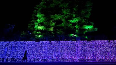 A woman walks along a wall decorated with ornate lighting in front of a hotel where the New Zealand rugby team is putting up in Beppu at the sport's world cup. AFP