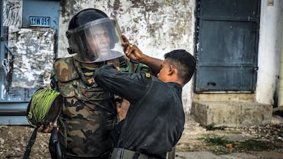 A bomb disposal guard is helped to don his equipment before heading to the scene of a suspect vehicle in Colombo, Sri Lanka, April 22, 2019. Jack Moore / The National.