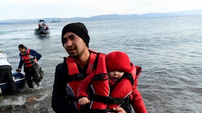 A migrant holds a baby as they arrive at the village of Skala Sikaminias, on the Greek island of Lesbos, after crossing the Aegean sea from Turkey. AP