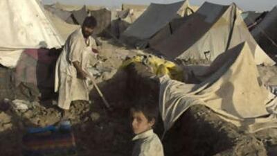 An Afghan homeless man, left, builds a frame for a tent as his son helps on the outskirts of Kabul.