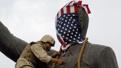 A US Marine covers the head of a statue of Iraqi President Saddam Hussein with the US flag before pulling it down in Baghdad's Al Firdos (paradise) square on April 9, 2003. Ramzi Haidar / AFP Photo