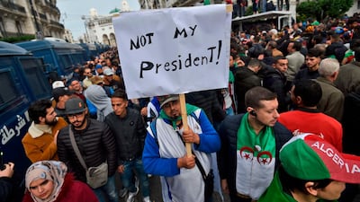 An Algerian protester lifts a placard in the capital Algiers as he takes part in a demonstration to reject the results of the presidential election, December 13, 2019. AFP