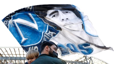 A man and child outside the Stadio San Paolo in Naples as a Diego Maradona flag is waved in tribute to the Argentine football legend following his death. Reuters