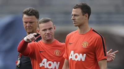 Manchester United's Wayne Rooney, left, talks with Jonny Evans as manager Louis van Gaal, left, watches during training for the their 2014 Guinness International Champions Cup soccer match against Real Madrid at Michigan Stadium in Ann Arbor, Michigan on Friday, Aug. 1, 2014. (AP Photo/Paul Sancya)