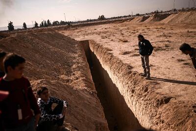 People stand next to a trench on the outskirts of Damascus believed to have been used as a mass grave. AFP