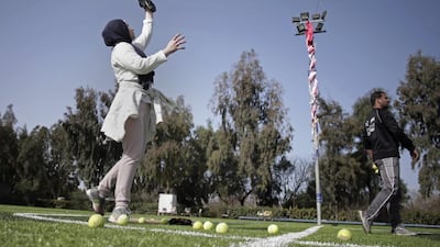 The female players wear hijabs, not helmets, toss around tennis balls, not baseballs and their leather gloves have been replaced by black imitations knitted from fabric.