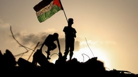 A Palestinian child waves the national flag atop the rubble of a destroyed building in the Bureij refugee camp in central Gaza. AFP