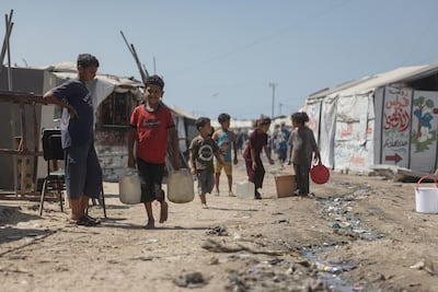 Palestinian children carry jerrycans past the tents of displaced people in Khan Yunis, southern Gaza. AFP