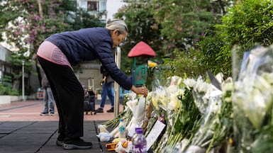 People place flowers near the scene after the deadly fire at Wang Fuk Court, Hong Kong. AP