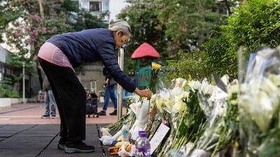 People places flowers near the scene after the deadly fire that started Wednesday at Wang Fuk Court, a residential estate in the Tai Po district of Hong Kong's New Territories, Saturday Nov. 29, 2025. (AP Photo / Chan Long Hei)