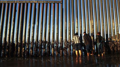 People peer through the US-Mexico border fence, towards San Diego, at the Pacific Ocean, in Tijuana, Mexico. Getty