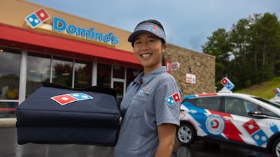 A Domino's delivery driver poses next to the company's new electric vehicles.
