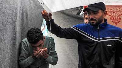 Men use their hands to drink rainwater dripping from the roof of a tent amid water shortages while at a school run by the UN Relief and Works Agency for Palestine Refugees in the Near East (UNRWA) in Rafah in the southern Gaza Strip. AFP