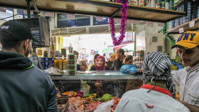 Workers serve customers at a poultry and food shop.