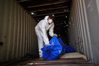 A man removes bodies from a container after they were released by Israel. AFP