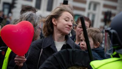 A woman holding a child and a heart-shaped balloon challenges Dutch riot police after they broke up a demonstration against coronavirus-related government policies including the curfew and tight lockdown in Amsterdam, Netherlands, on March 21, 2021. AP