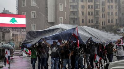 Protesters cover them selves by a tent as they block the Achrafieh highway in downtown Beirut. EPA