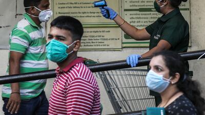 A female security guard scans the customers as a precaution against the ongoing pandemic of the Covid-19 disease, arriving to buy groceries at a D-mart mall in Mira road on the outskirts of Mumbai, India. EPA