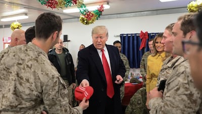 US President Donald Trump holds a Make America Great Again hat to sign as he and first lady Melania Trump greet military personnel at the dining facility during an unannounced visit to Al Asad Air Base, Iraq. Reuters