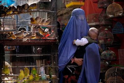 A woman walks through a bird market as she holds her child, in Kabul, Afghanistan, in May 2022. AP
