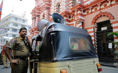 A Sri Lankan police officer announces security warnings urging people to be cautious around abandoned vehicles and parcels, in a street outside a mosque in Colombo. AP