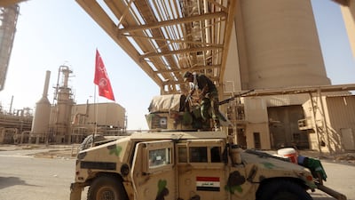 An Iraqi Shiite fighter cleans his weapon on his vehicle at the petrochemical plant in the town of Baiji, north of Tikrit, on October 16, 2015.