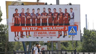 People walk by under a poster advertising Shakhtar Donetsk in downtown Donetsk, Ukraine, on July 23, 2014. The club have moved their operations to the west of the countries with violence still prevalent in the east. Robert Ghement / EPA