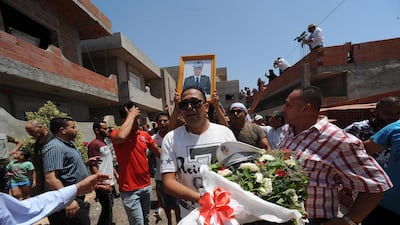 A man carries flowers and the police hat of Sgt Arbi Guizani, as others carry his picture and body during his funeral on July 9, 2018, in Ettadhamen, a suburb of the capital Tunis. EPA