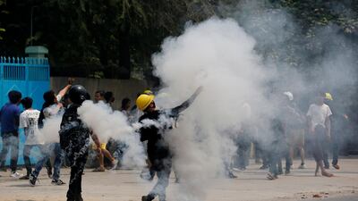 Protesters hurl back tear gas canisters towards police in Mandalay. AP Photo
