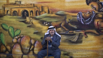 Palestinian refugee Abdul Ghafour Abdulrahman, 85, who witnessed what the Palestinians call the “Nakba,” or “catastrophe” referring to their uprooting in the war over Israel’s 1948 creation, sits in front of a wall painted with a mural depicting the Israeli-Palestinian conflict in the Kalandia refugee camp, between Jerusalem and the West Bank city of Ramallah.