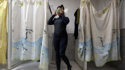 A woman wearing a wetsuit, mask and flippers prepares to take to the water for a training session in Basra, Iraq. Reuters