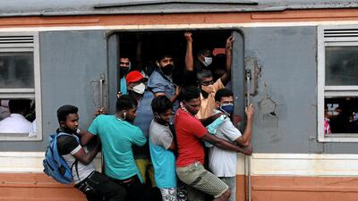 Passengers hang on to a train during the daily commute in Colombo, Sri Lanka. Reuters