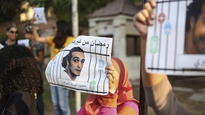 Egyptian women raise posters with people detained for violating the country's protest law as they hold a rally outside a presidential palace in Cairo, Egypt. Mohamed el Raai / AP Photo