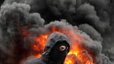 A Palestinian man is pictured in front of burning tyres during clashes between Israeli troops and Palestinian protesters in the village of Kfar Qaddum near the Jewish settlement of Qadumim (Kedumim) in the occupied West Bank. AFP