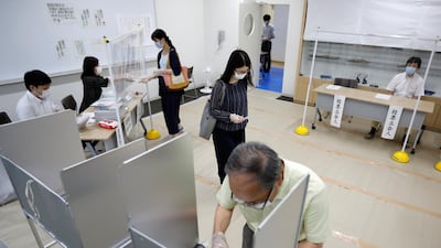Voters and members of Election Management Committee wearing protective face masks are seen at a voting station for the Tokyo Governor election, in Tokyo, Japan. Reuters