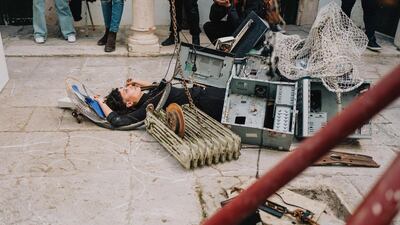 Artist Rym Hayouni performs her piece using e-waste she found along the beaches and streets of Tunis. The audience is encouraged to pile on scraps as Hayouni lies serenely under the rubble of our collective obsession with short-lived electronics. Erin Clare Brown / The National