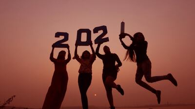 Indian girls are silhouetted against the setting sun as they hold cutouts of digits and a syringe while celebrating the upcoming new year in Bhopal, India. EPA