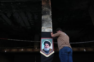 A photo of the late Hezbollah leader Hassan Nasrallah hangs in a damaged building in Beirut. EPA