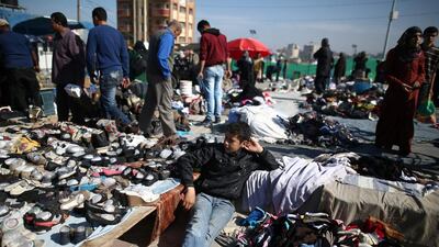 A Palestinian boy sits amidst used clothes and items at the weekly flea market in the Nusseirat refugee camp, central Gaza Strip, on February 29, 2016. / AFP / MOHAMMED ABED