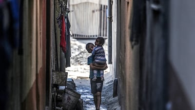 A Palestinian boy carries a toddler in Deir El Balah in the central Gaza Strip on May 15. AFP