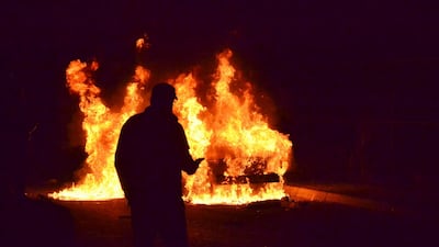 A man passes in front a car that was set on fire during a protest against strict lockdown measures in Tripoli. AP