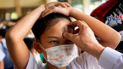 A lay minister uses ashes to draw a cross on the forehead of a pupil at an elementary school in Paranaque City, Metro Manila, Philippines. Reuters