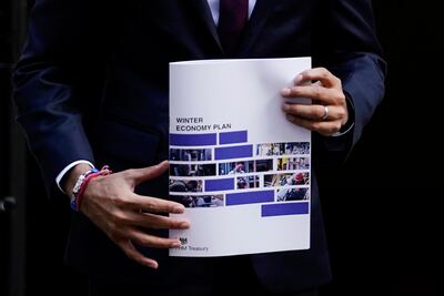 Mr Sunak holds a copy of his 'Winter Economy Plan' outside 11 Downing Street in London on Thursday. EPA