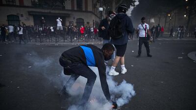 A Paris Saint-Germain fan picks up a tear gas canister. Getty