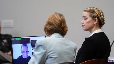 Amber Heard listens as Depp's former lawyer Adam Waldman appears on a monitor. AP